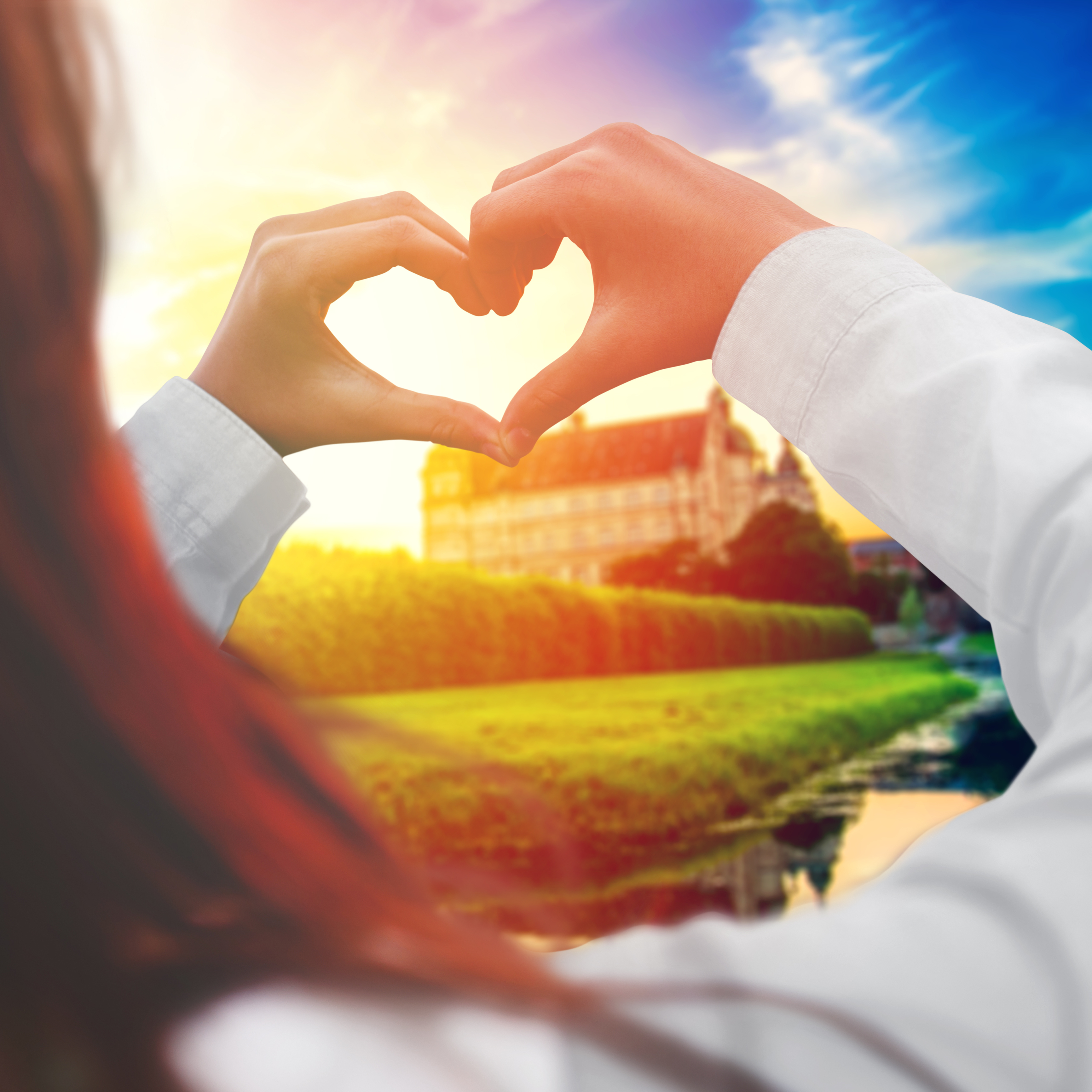 Hands making heart greeting with castle in background
